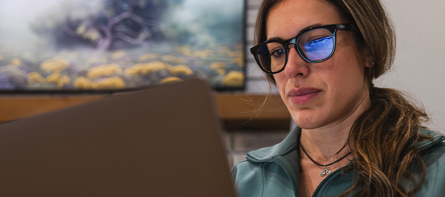 Woman wearing Smith blue light glasses while workin on a laptop.