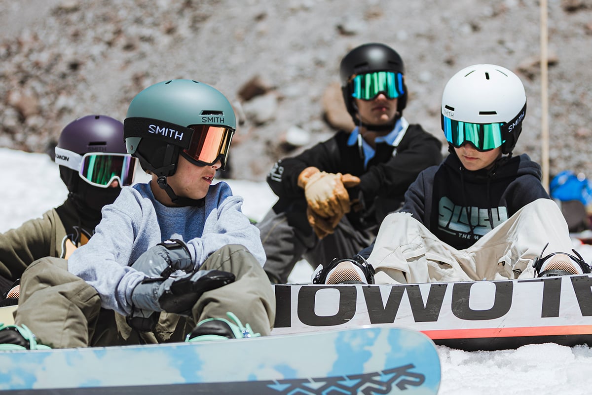 A group of young snowboarders hang out at mount hood, all wearing the Smith Rodeo Jr Snow Helmet